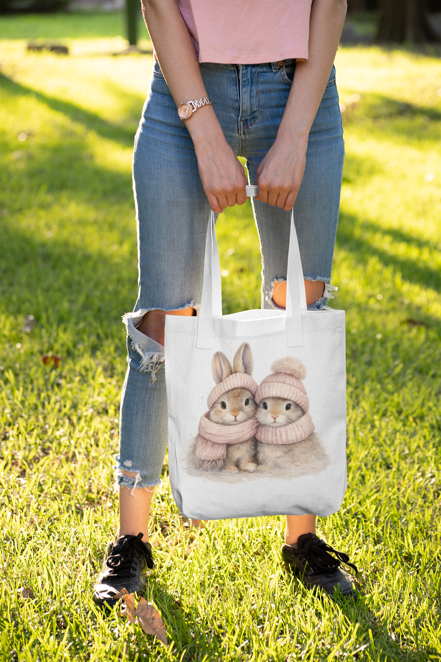 Person holding a tote bag with cartoon bunnies on grass